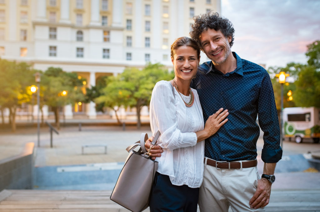 middle aged couple posing for a photo outside a building
