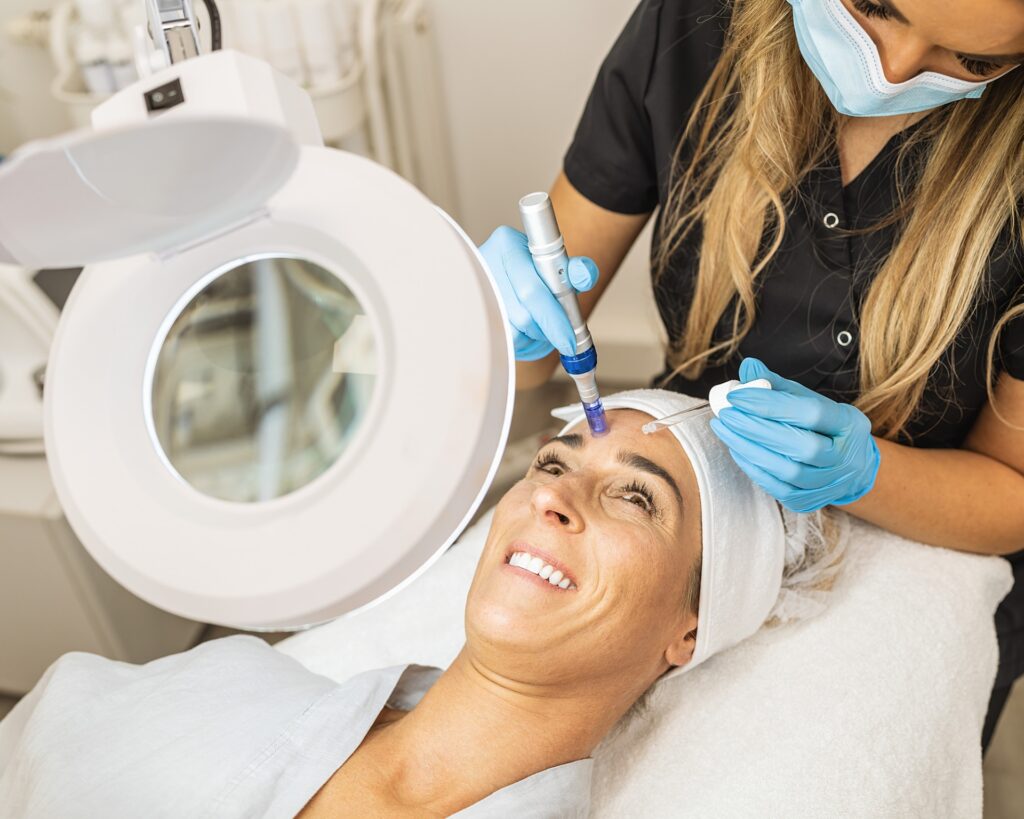 A woman in a robe lying on a treatment table receives one of the best facials in Cincinnati from a female injector at Amy Brenner, MD & Associates.