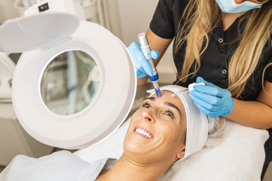 A woman in a robe lying on a treatment table receives one of the best facials in Cincinnati from a female injector at Amy Brenner, MD & Associates.