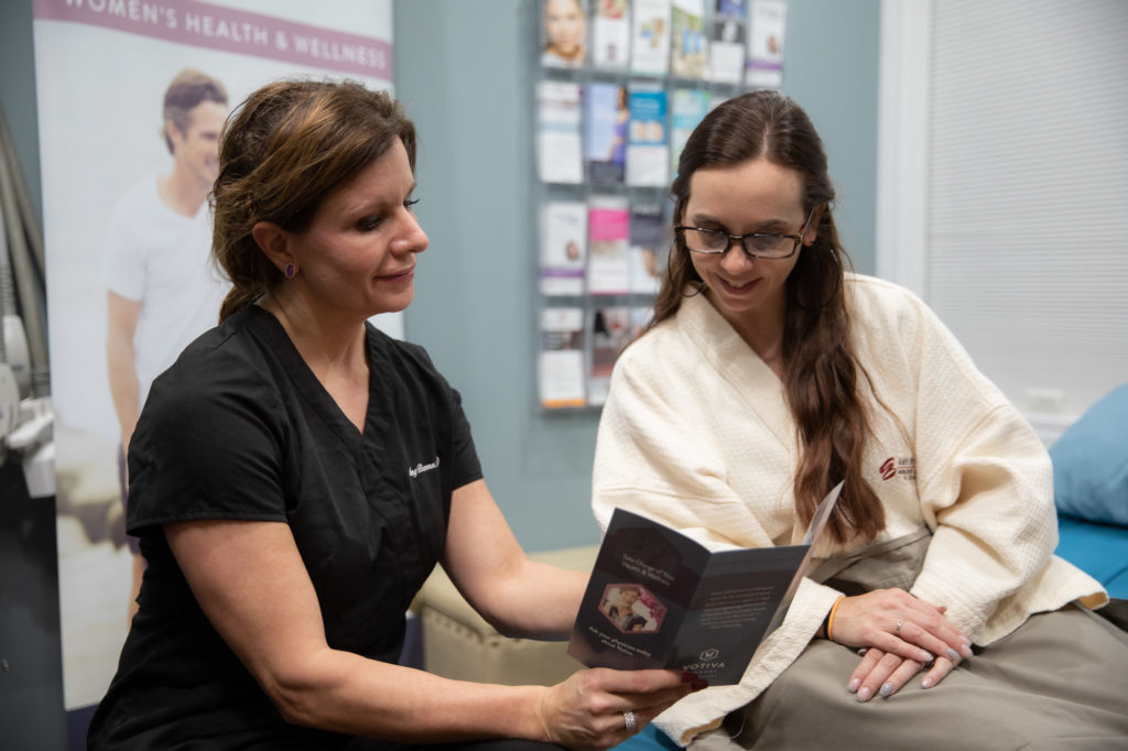 A medical provider sitting with a female patient, showing her an informative brochure about women’s sexual wellness in Cincinnati.