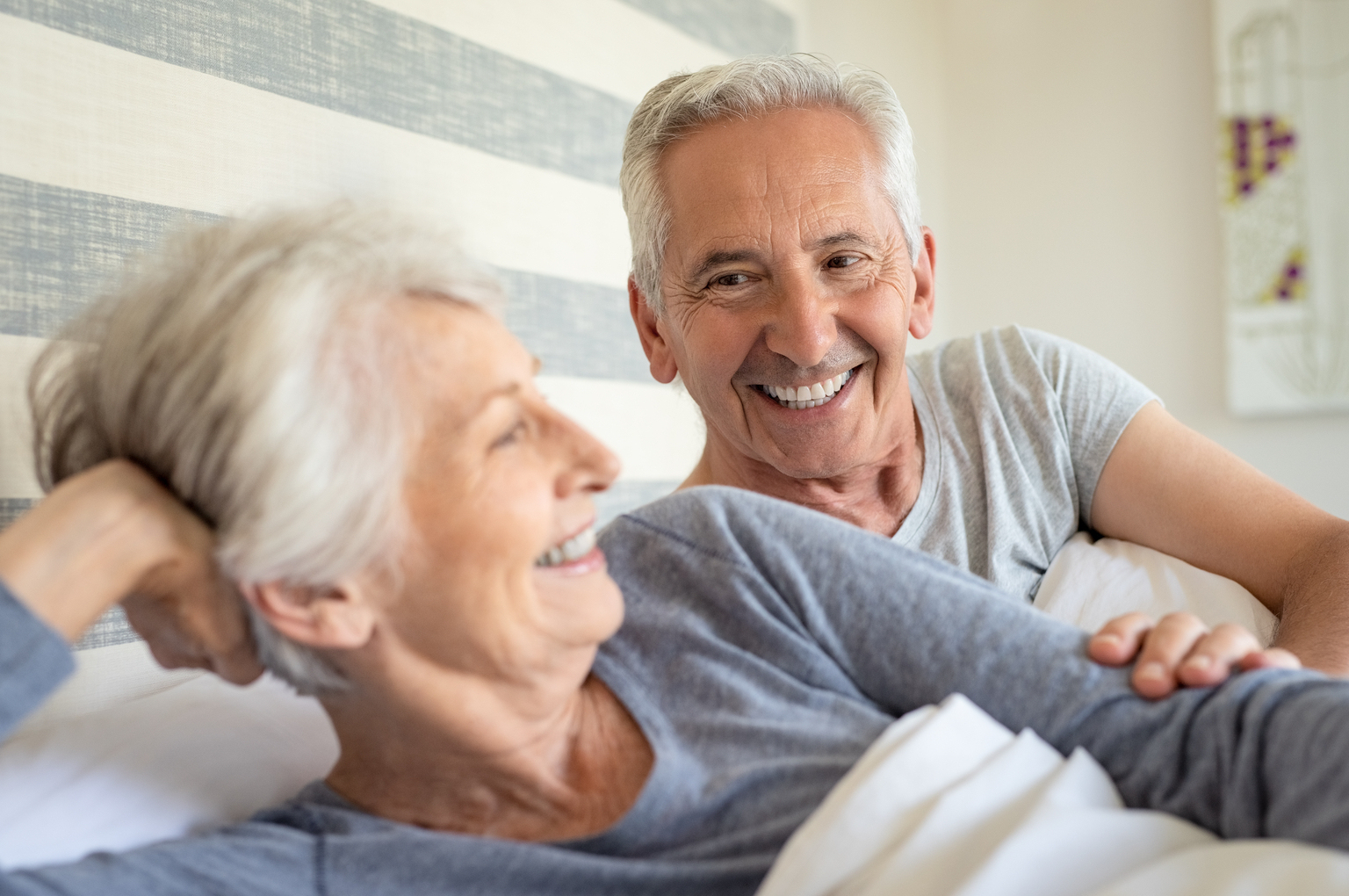 older couple smiling in bed after erectile dysfunction treatments in Cincinnati