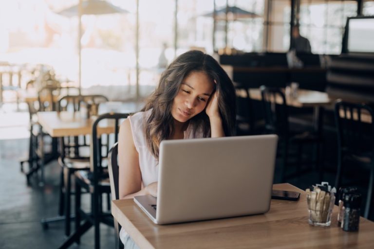 woman taking a hormone therapy candidacy quiz on her computer sitting in a cafe