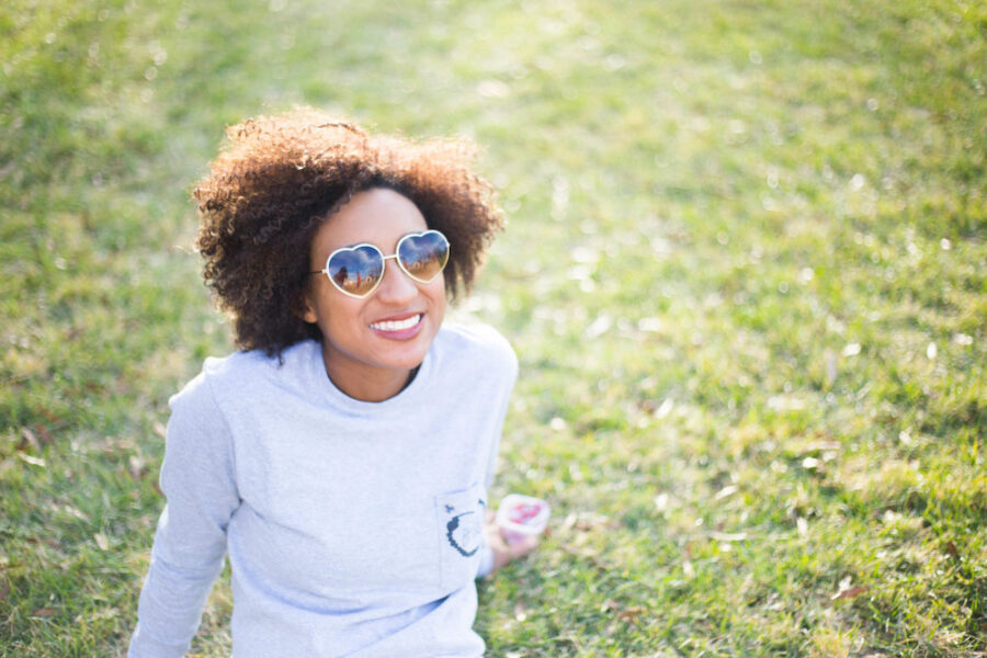 woman outside enjoying the sun wearing heart-shaped sunglasses