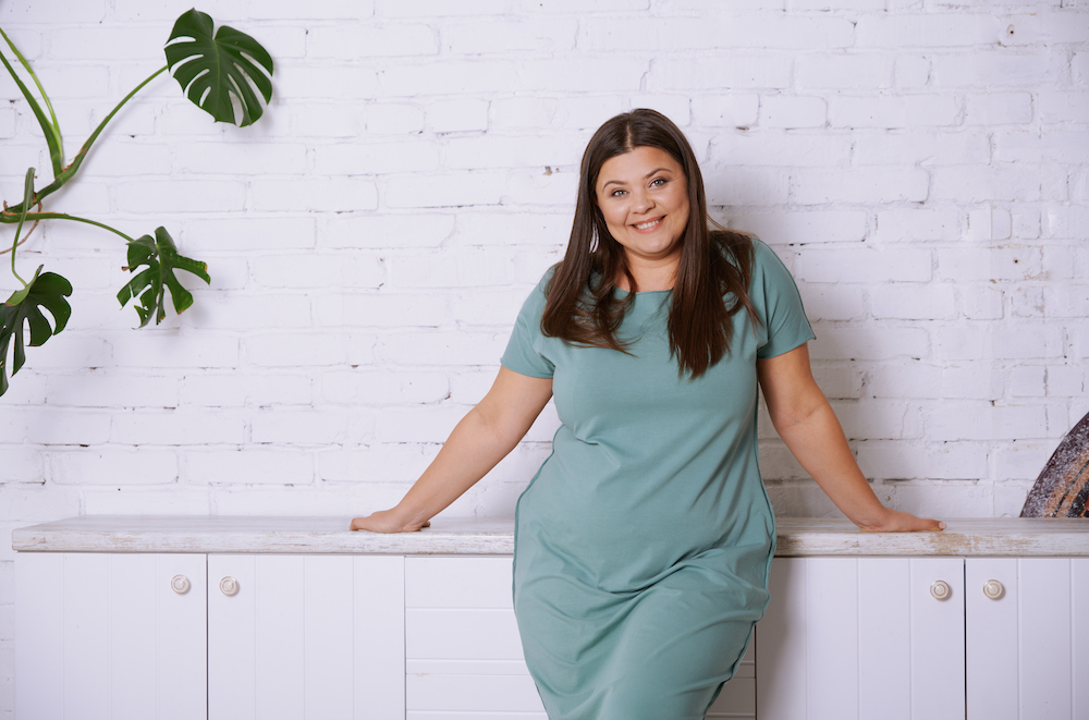 plus sized mid size woman at home in a blue dress smiling