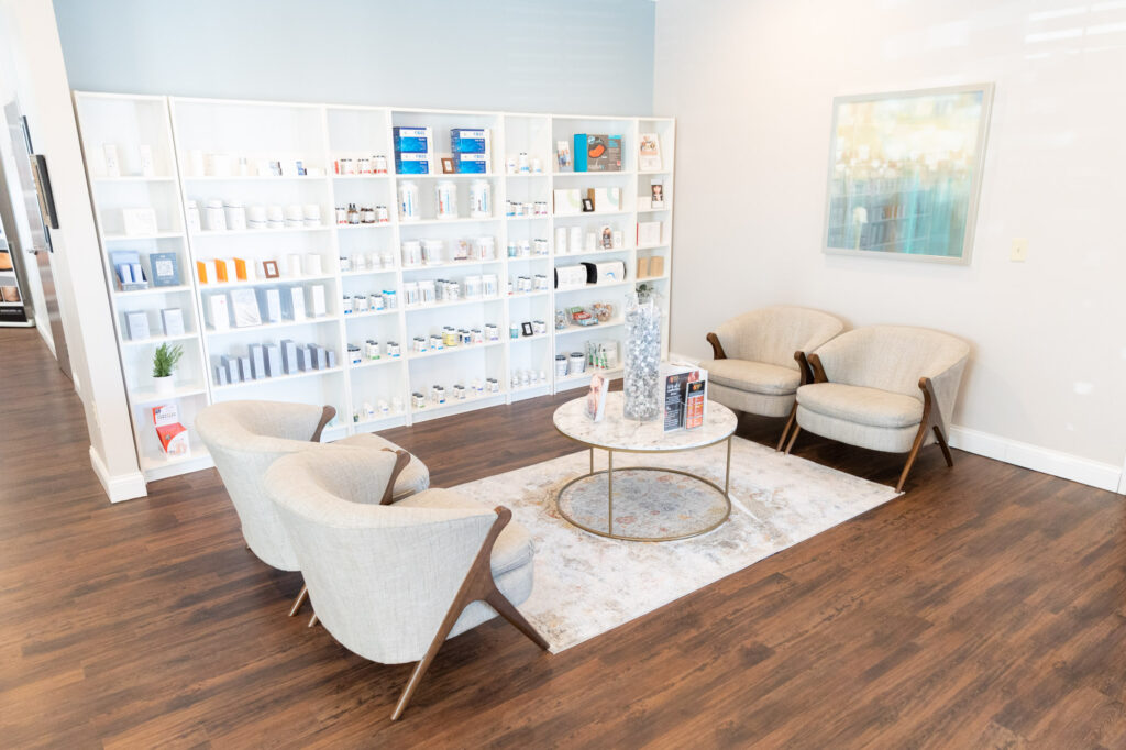 The lobby of an IV clinic in Cincinnati, comprising a wall of skincare shelves and a coffee table and chairs.