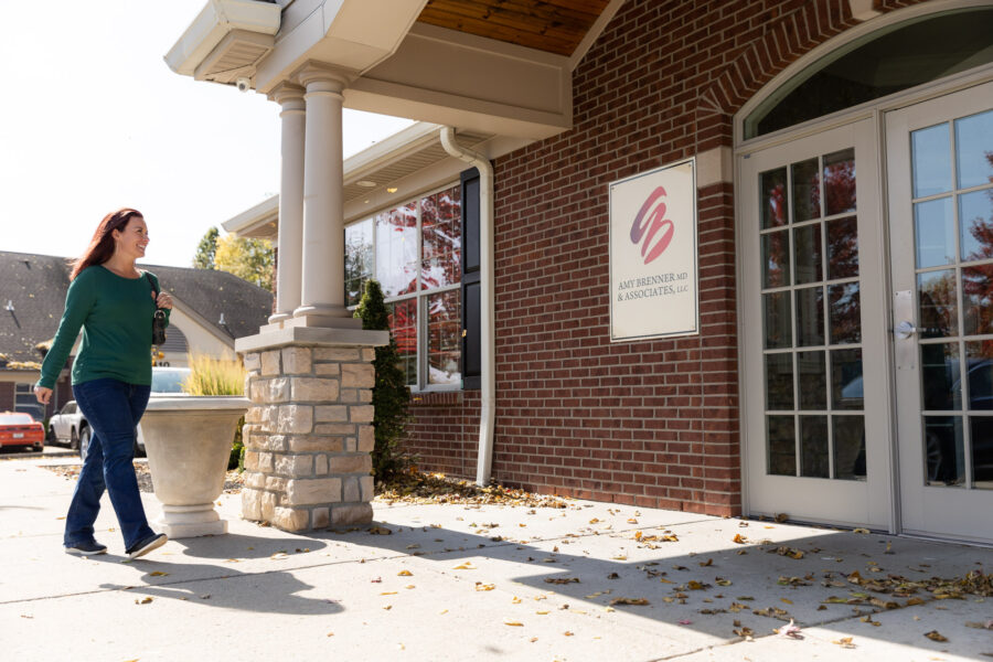 Woman walking up to the front doors of Amy Brenner MD & Associates to go to their med spa in Kenwood.