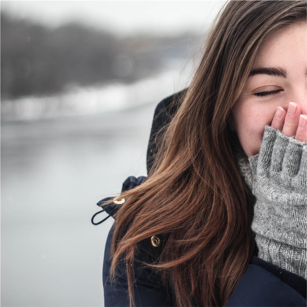 woman outside in winter covering her face wearing gloves