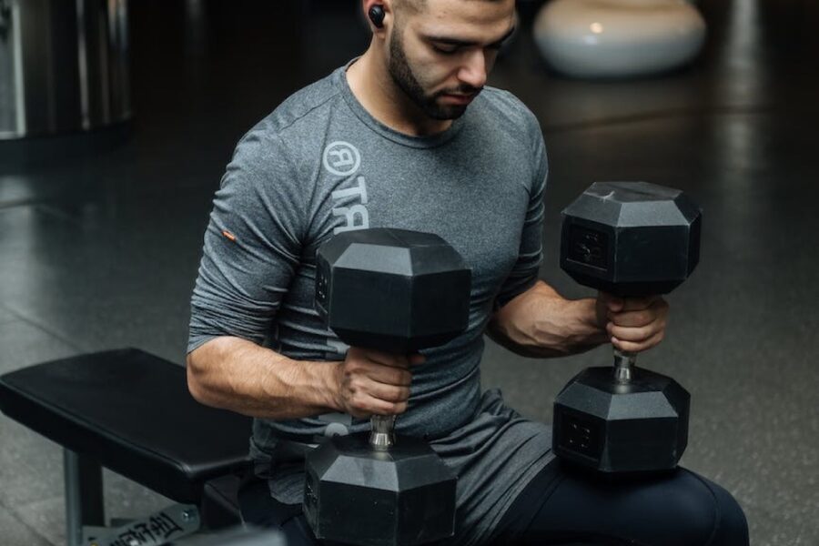 man sitting on workout bench holding dumbbells