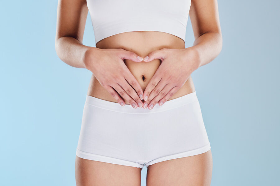 Woman holding her hands in a heart shape over her stomach after learning how to improve gut health