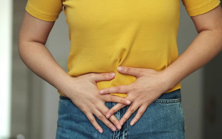 Woman holding her stomach, wondering "What is Leaky Gut Syndrome?"