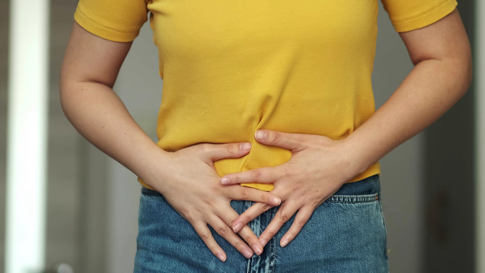 Woman holding her stomach, wondering "What is Leaky Gut Syndrome?"