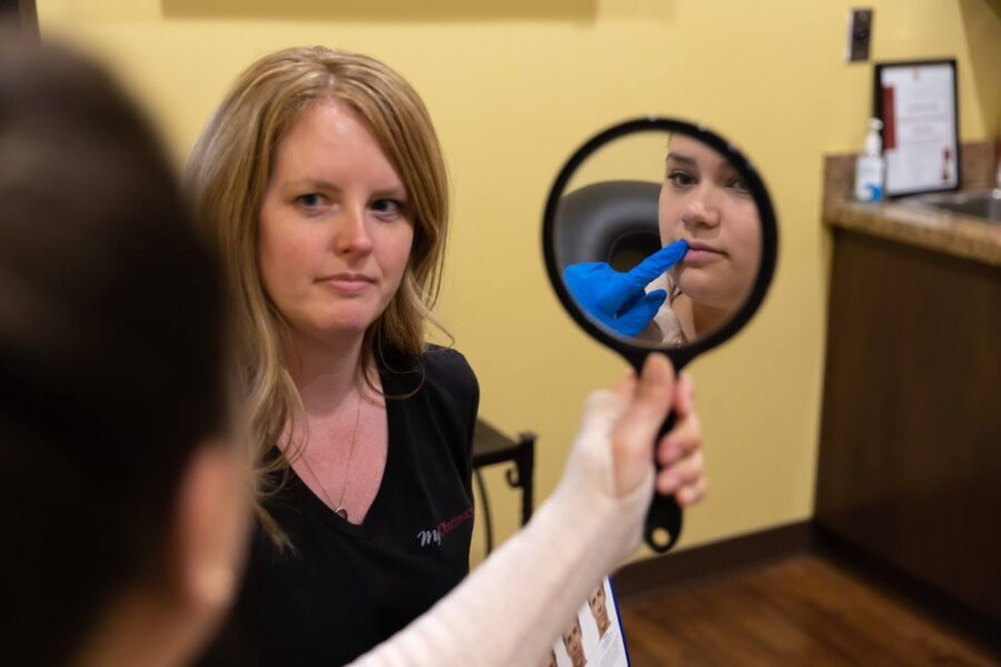 A woman is looking at her Botox & Filler in Hyde Park, OH in a mirror
