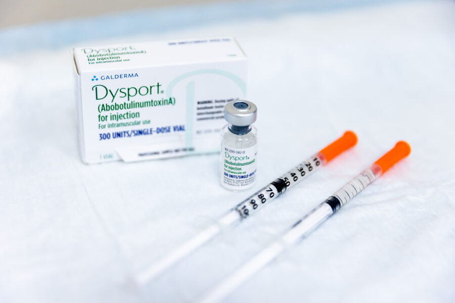 A box and vial of Dysport in Mason, OH, next to syringes, all lying on a white table.
