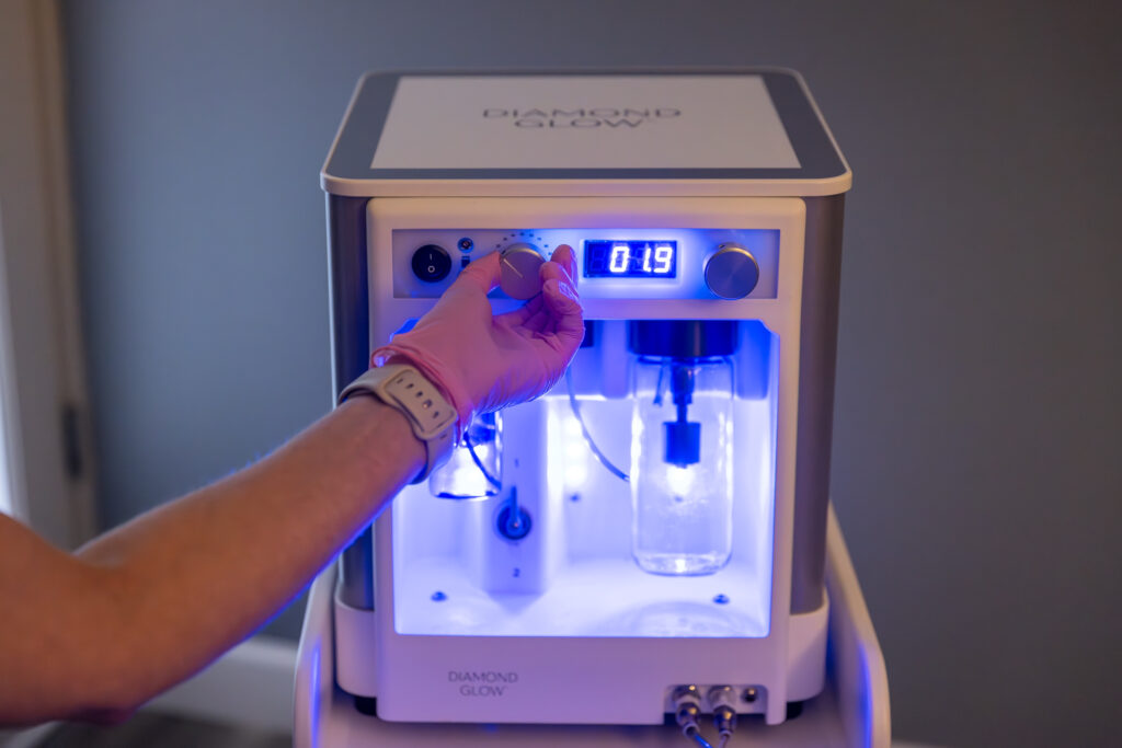 A gloved hand adjusts a setting on the DiamondGlow device for facials in Cincinnati.