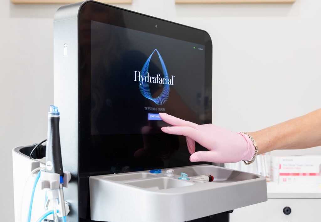 The Hydrafacial control screen as a gloved hand reaches to press a button for one of the most amazing facials in Cincinnati.