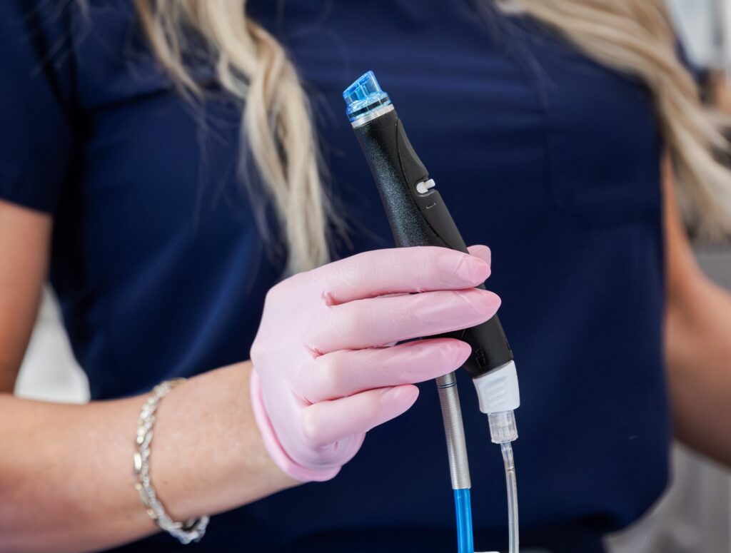 Close up of a woman in scrubs and gloves holding the Hydrafacial applicator, which can help with acne treatment in Cincinnati.